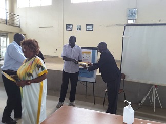 Amuru District CAO receiving PDM training manuals from Minister Hillary Onek